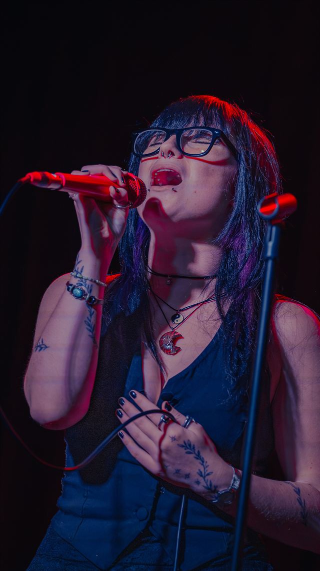 A singer holding a red microphone with both hands