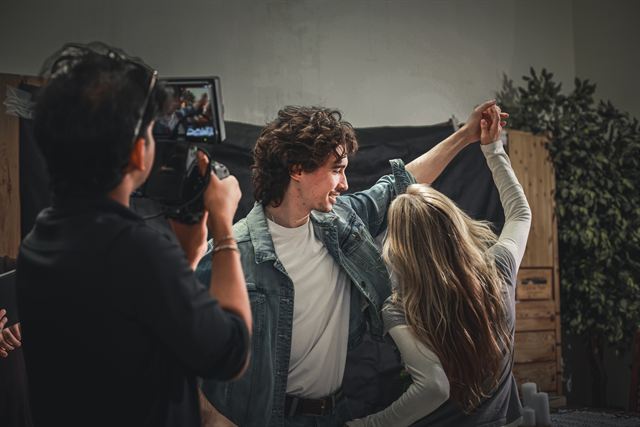 A camera operator filming two actors mid-dance