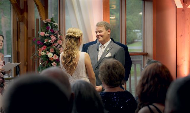 The bride walking towards the groom past the seated guests